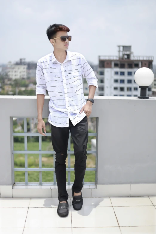 a man with sunglasses and a pair of black pants stands on the ledge