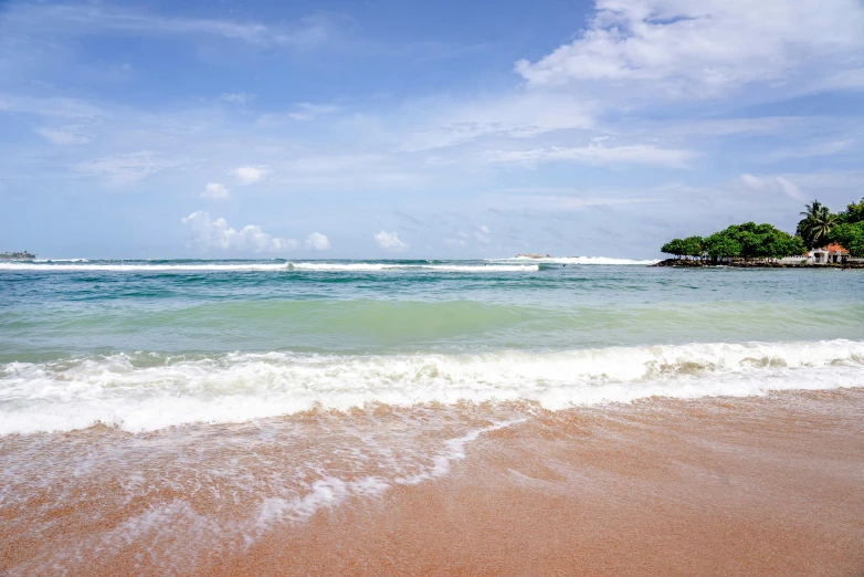 a beach on the ocean with small houses in the distance