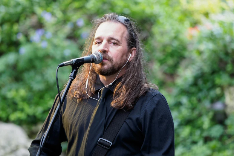 a man with long hair on stage singing into a microphone