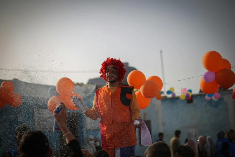 the clown looks up and smiles as balloons are thrown into the air