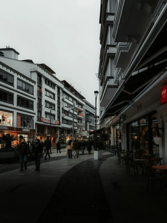 a group of people walking down a street next to a tall building