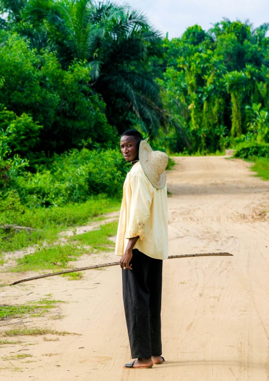 a man standing in the middle of a dirt road holding soing