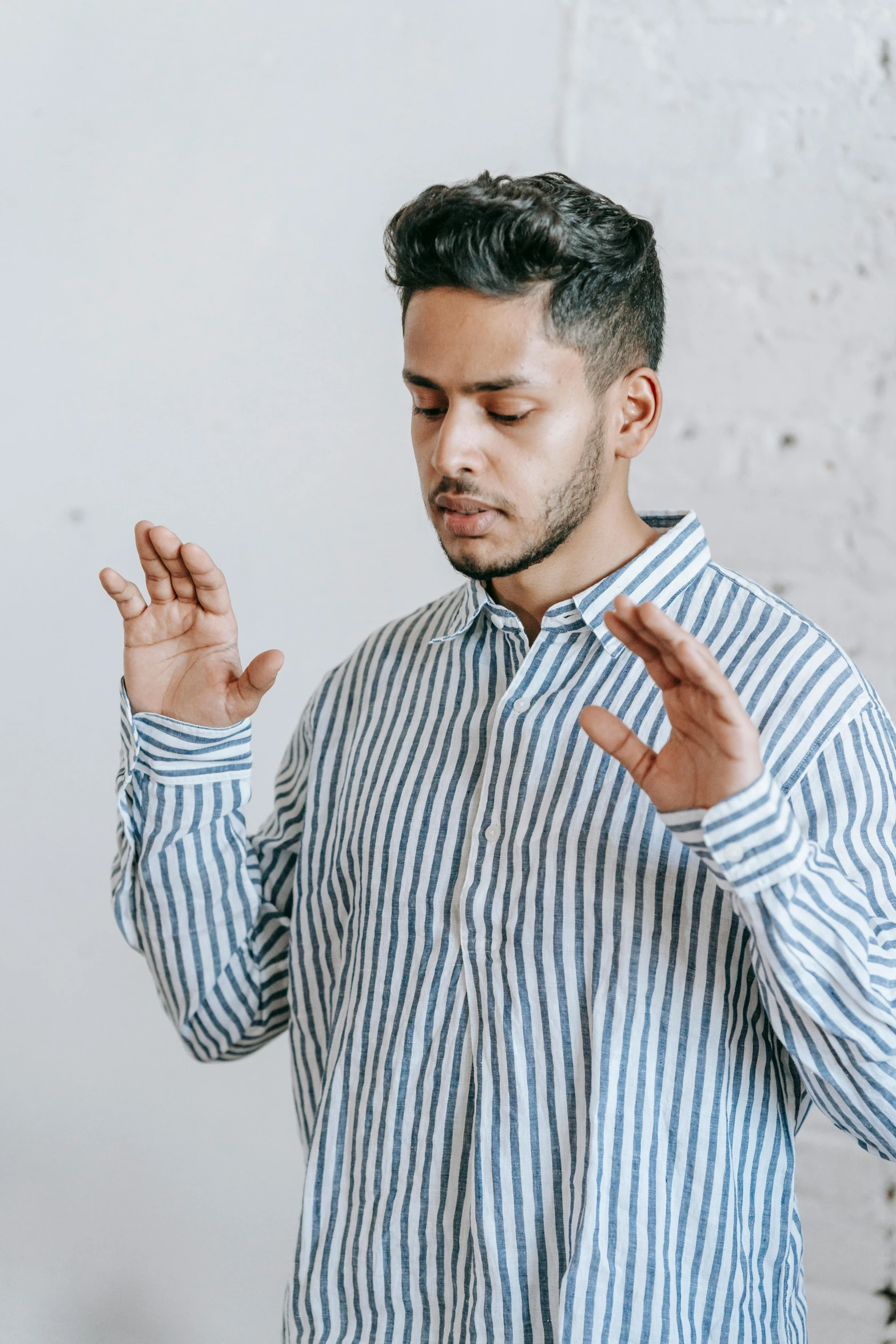 man standing in front of white wall with hands crossed