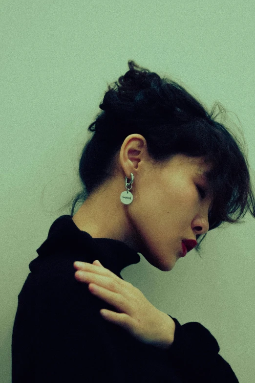 woman in black shirt wearing earrings and posing with her head back