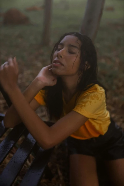 a woman sits on a bench in the woods