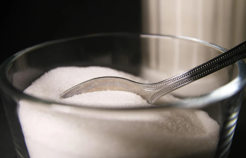 a glass full of white sugar with spoon