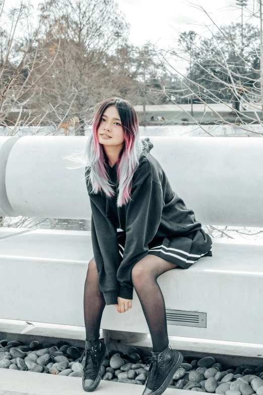 a woman wearing a fuzzy black hoodie sits on a white bench in the snow