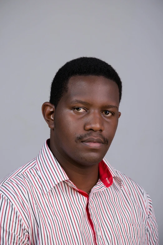 a young black man in a white and red striped shirt poses for the camera