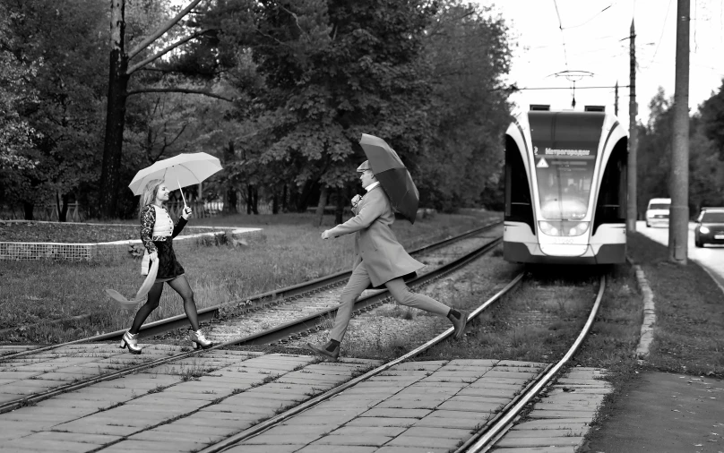 two women in short skirts are walking down train tracks