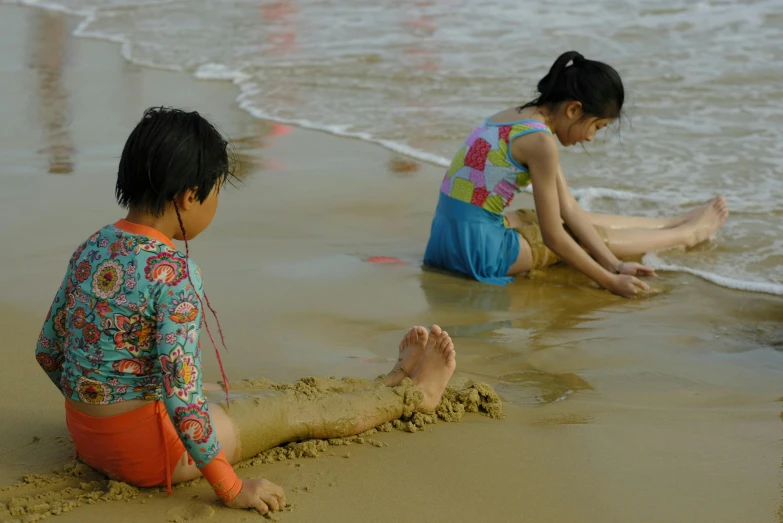 two little s sitting in the water at the beach