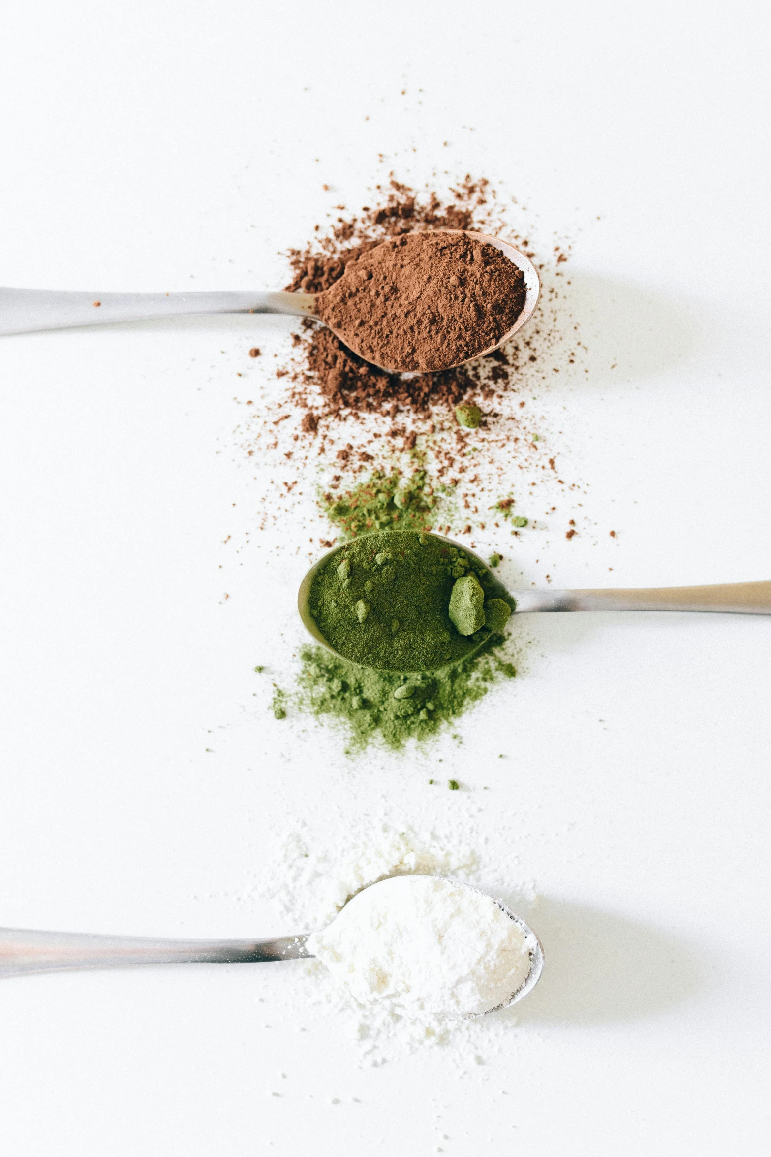 various spices and powders next to two spoons