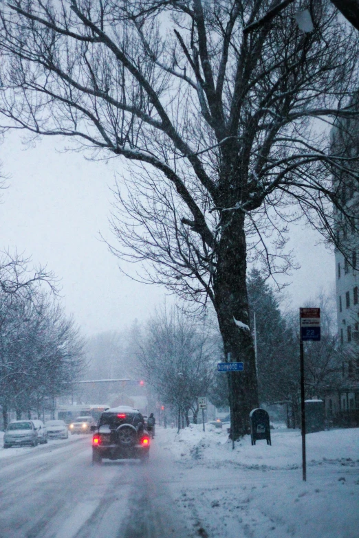 a red car driving down the road in winter