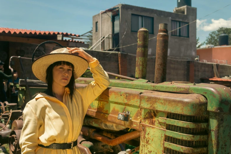 a woman is standing beside a green farm tractor