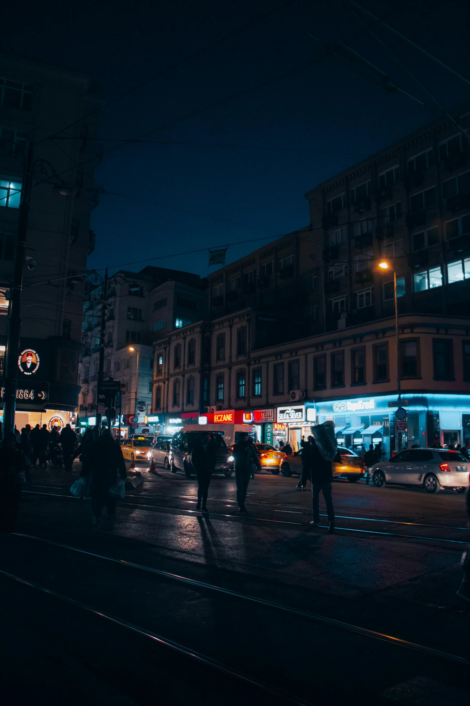 people walking on a wet city street in the dark