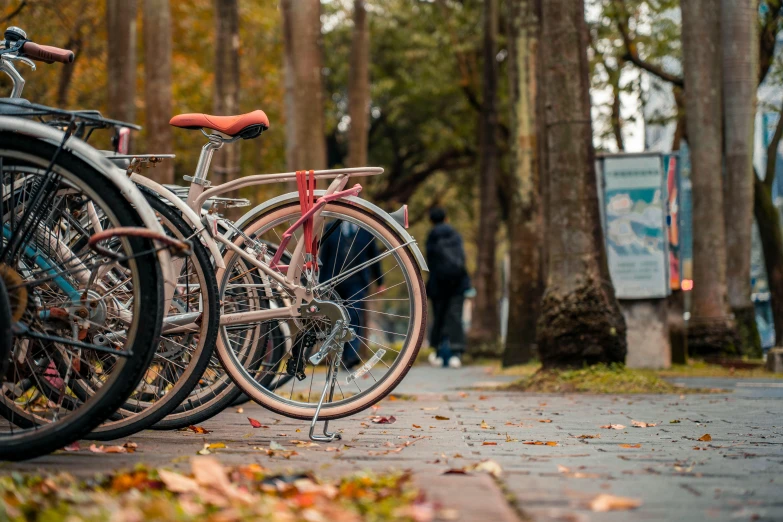 a parking lot with several parked bikes and a man walking on the sidewalk