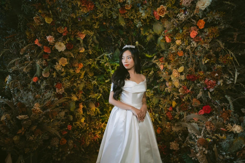 young woman dressed in white standing by a fake floral wall