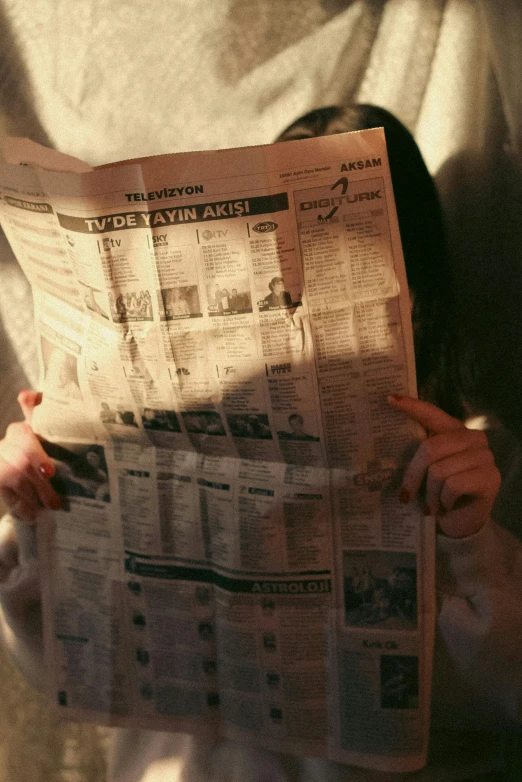 a person reads a newspaper while holding a dog