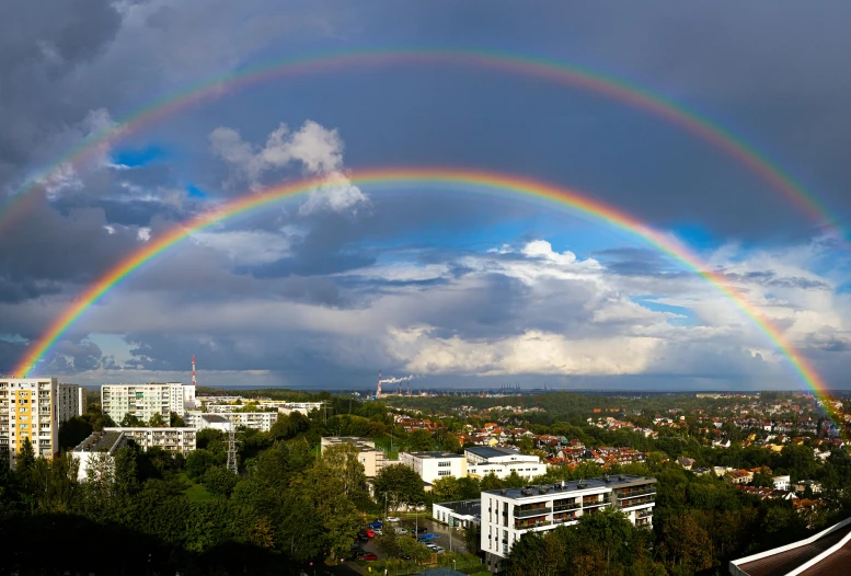 a rainbow over a city with trees and buildings