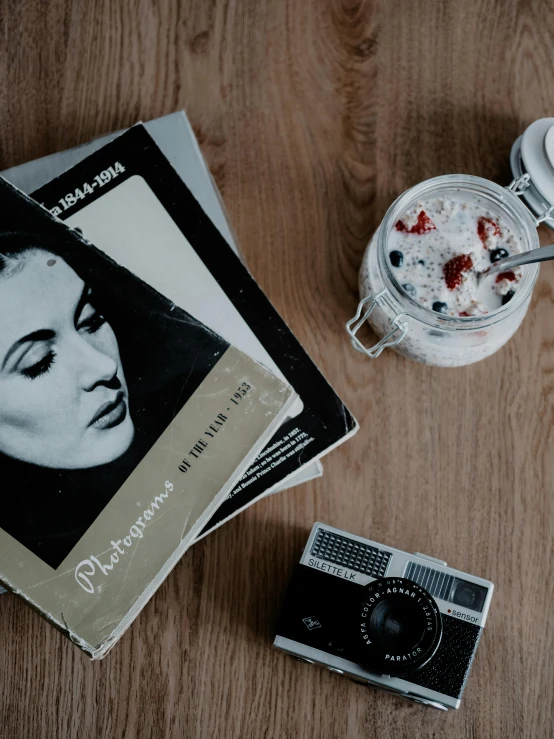 an old camera sitting next to a recipe book and glass of water