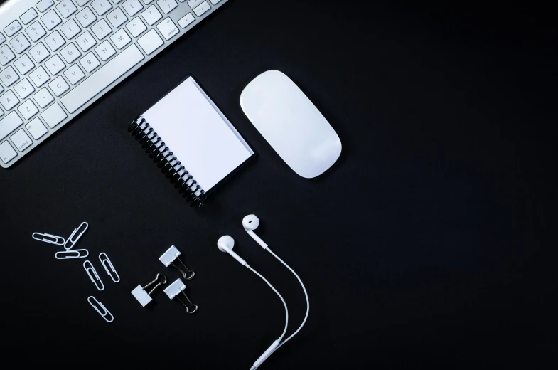 an apple computer with ear buds, headphones, keyboard and accessories