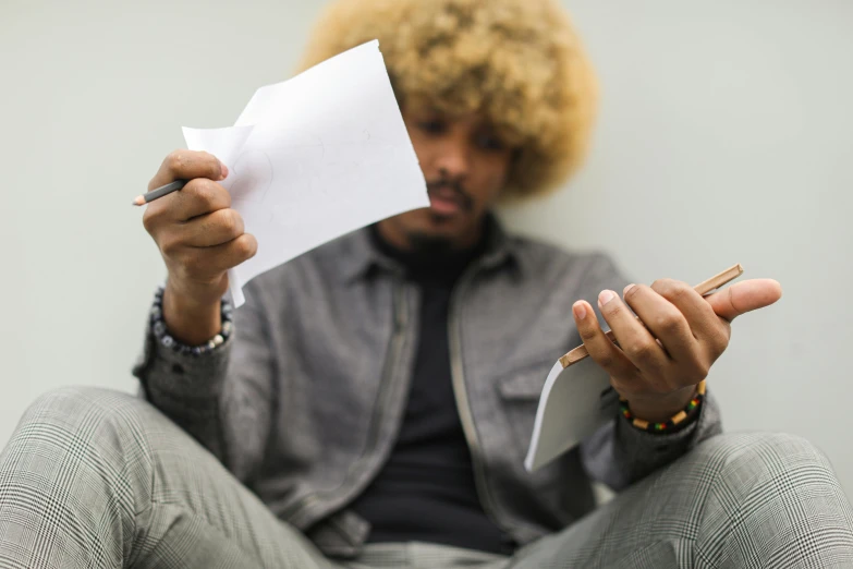 a young man smoking a cigarette, holding up a piece of paper