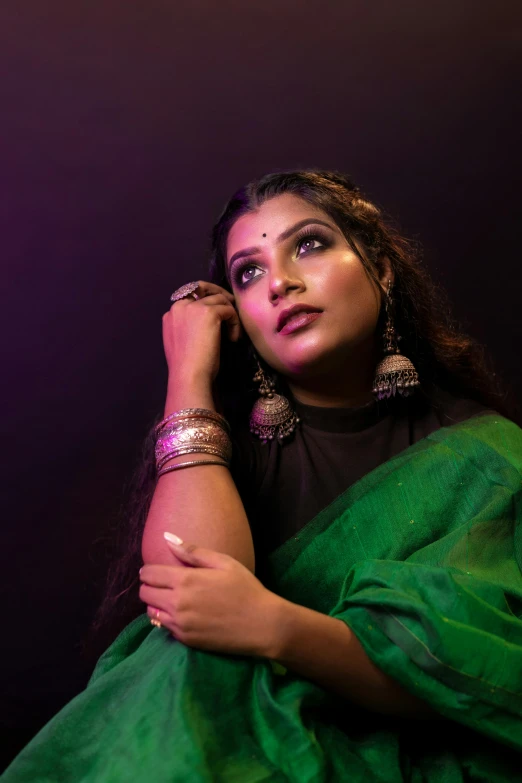 woman in green and gold saree looking up at the camera