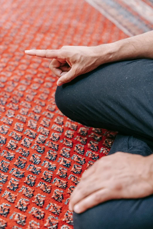 the person is holding their hand out and sitting on an orange carpet