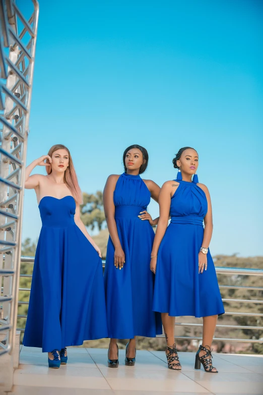 four beautiful women in blue dresses standing outside