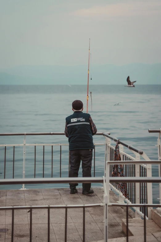 a man is fishing from the side of a pier