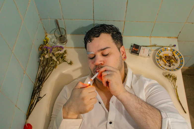 a man laying in a bathtub with his eyes closed and nose covered with an electric toothbrush
