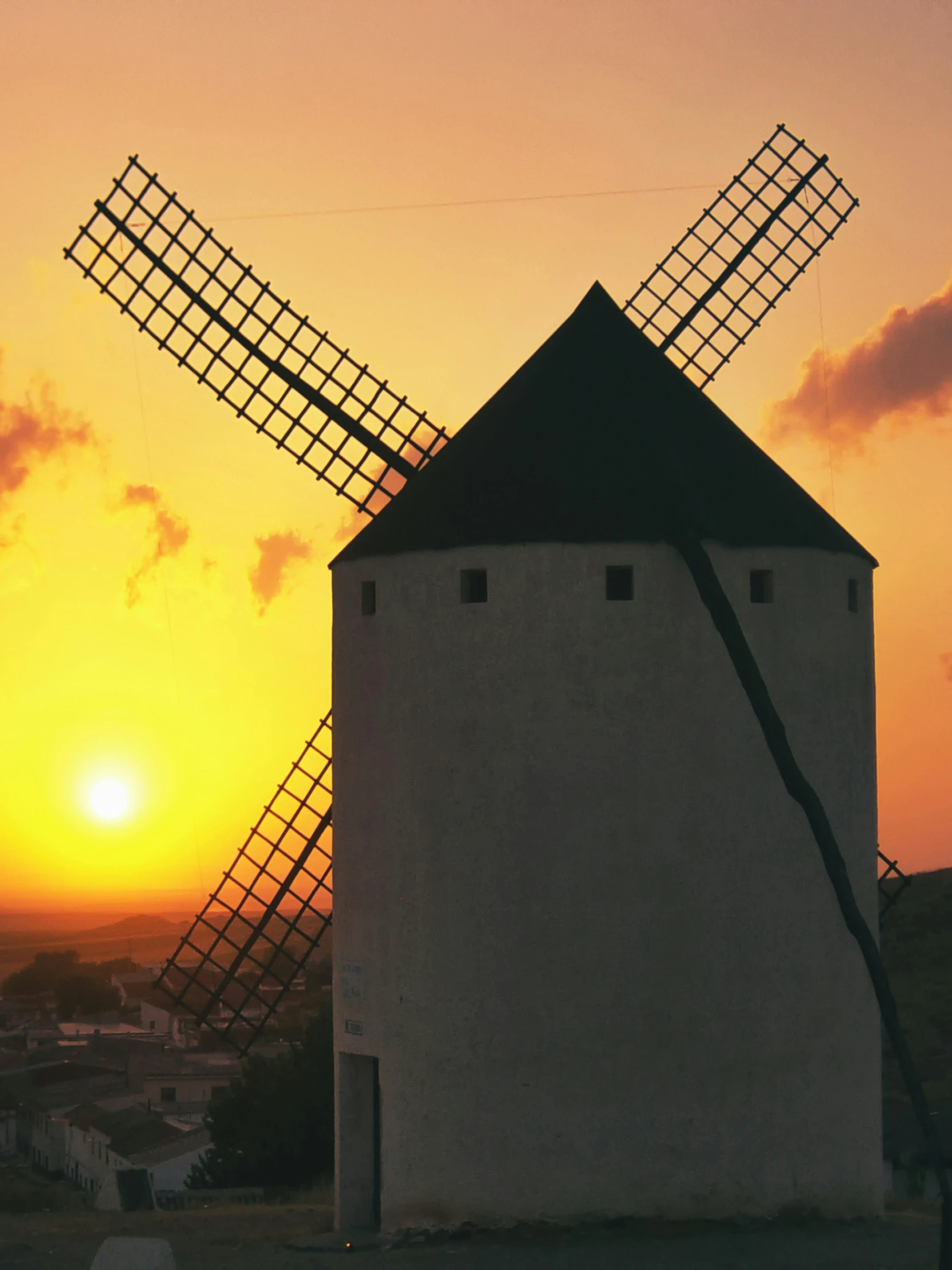 the sun rises behind an old windmill on the hill