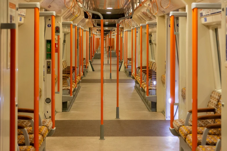 the inside of a bus with orange poles and chairs