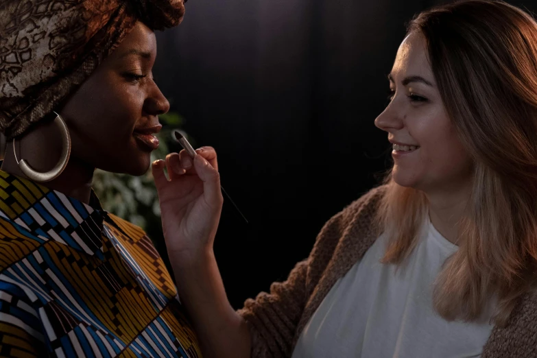 two women in a black room talking and laughing