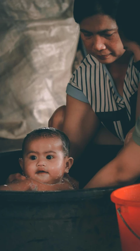 a woman is washing a baby in the tub