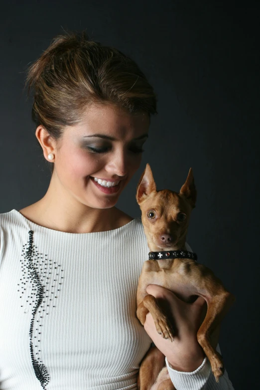 a smiling woman holding a small dog on her arms