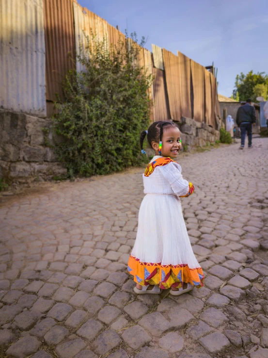 an adorable young child standing on a cobblestone walkway