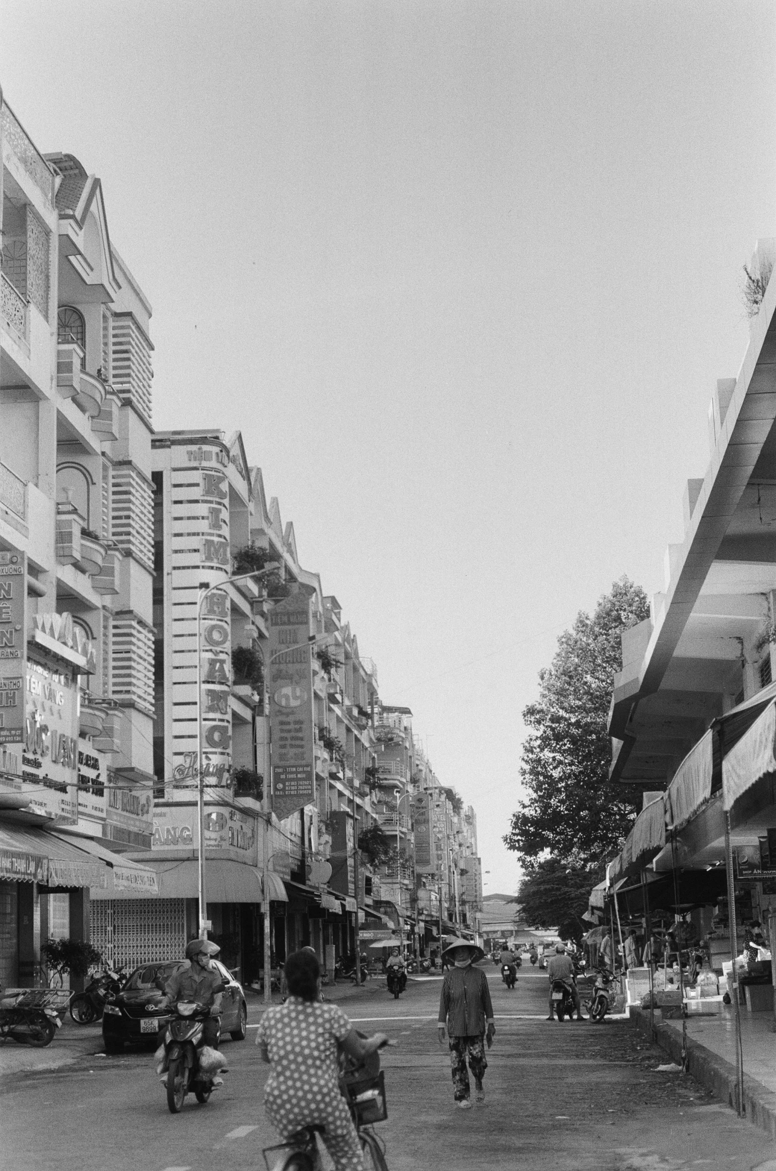 this black and white pograph shows a street with old fashioned shops