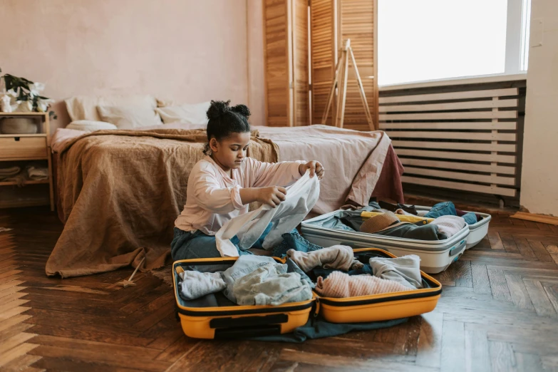 a girl in a room sitting on the floor with an open suitcase