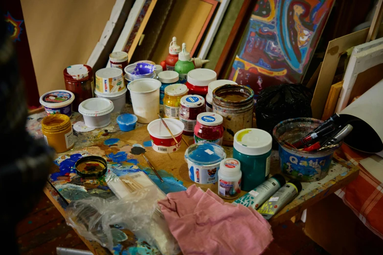 a messy desk full of paints, crafting supplies and tools