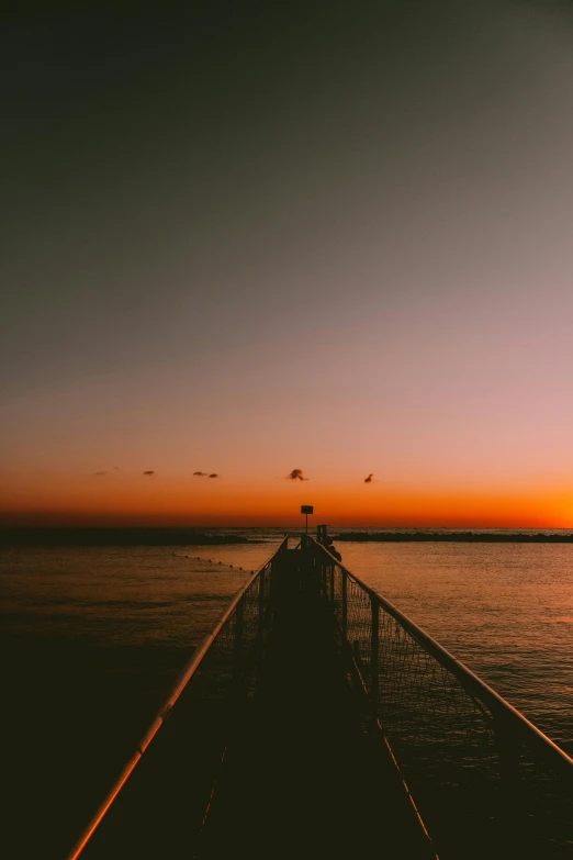 the sun sets as the sky reflects in the calm water