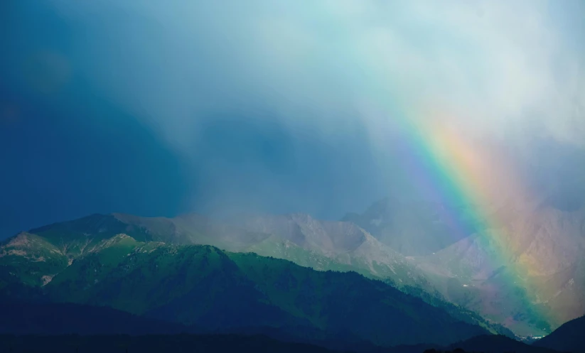 a rainbow is seen with the mountains in the background