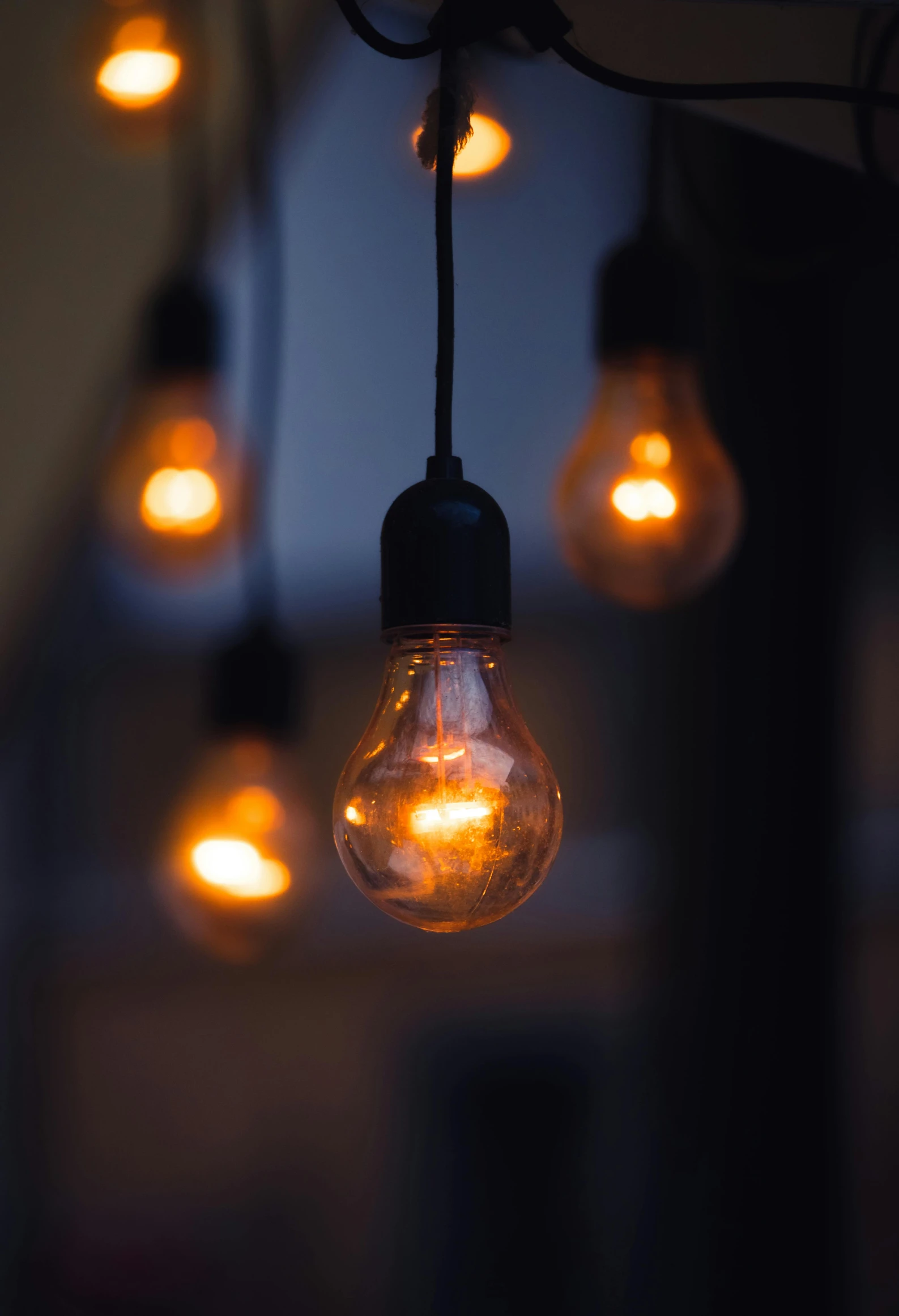 light bulbs suspended in a room with some one turned on