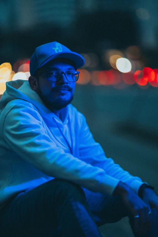 a man wearing glasses and a blue hat sits in a city park