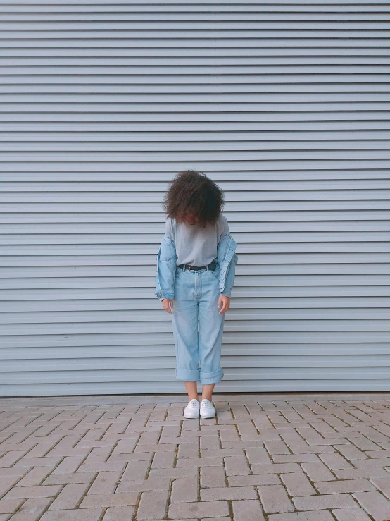 a young woman in high - rise jeans with her hair back to the camera