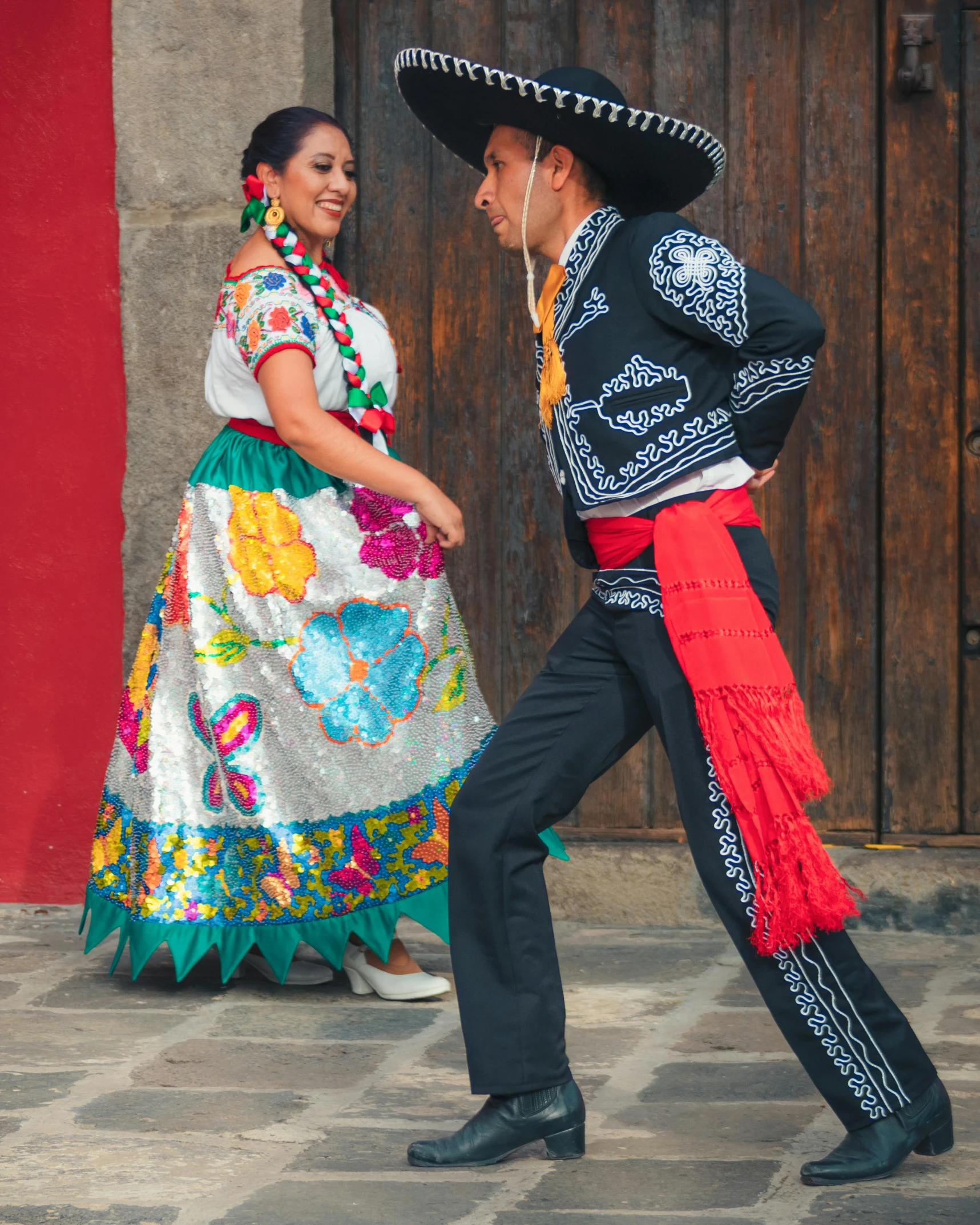 a couple wearing the traditional mexican costume and hat dance together