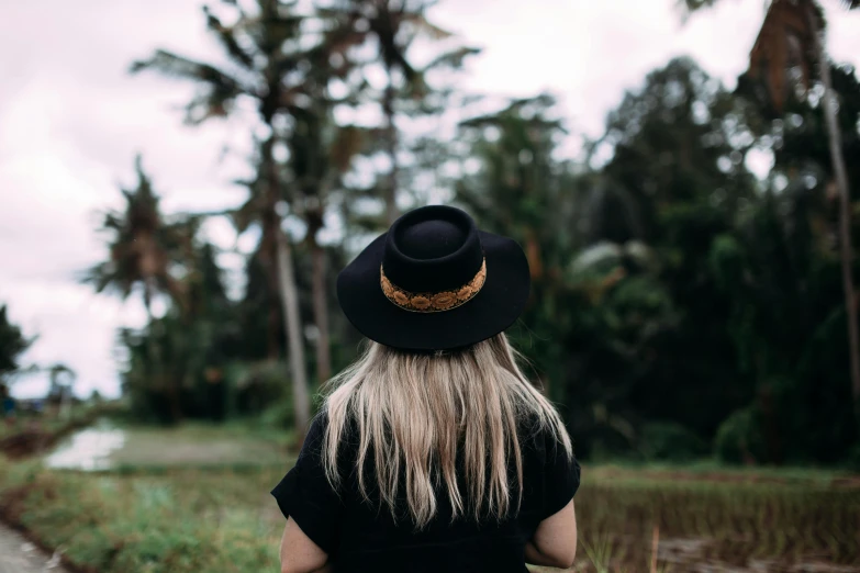 a woman standing alone near trees looking at soing