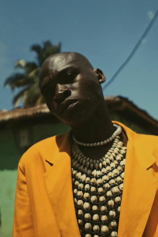 a black man in a yellow suit is standing outside