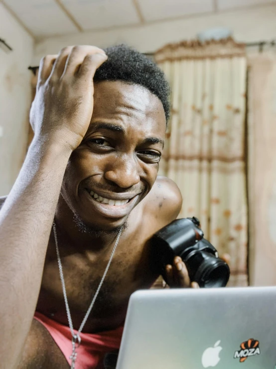 a woman looking at her camera while holding a laptop