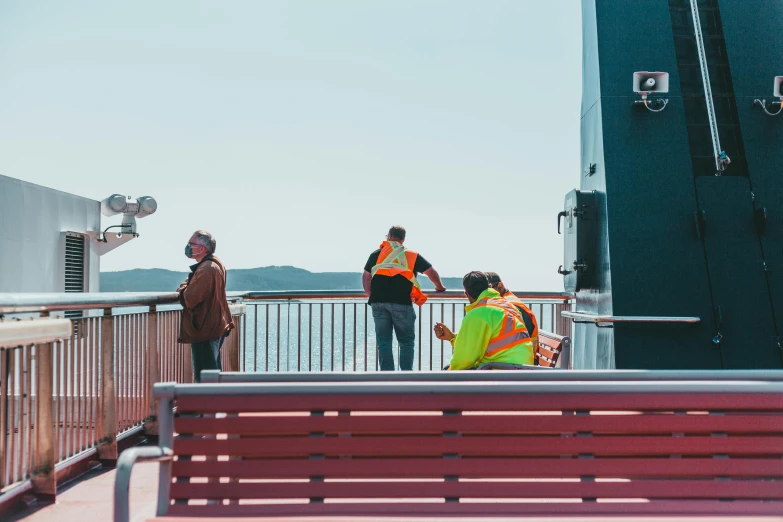 three people on a bridge looking out onto the water