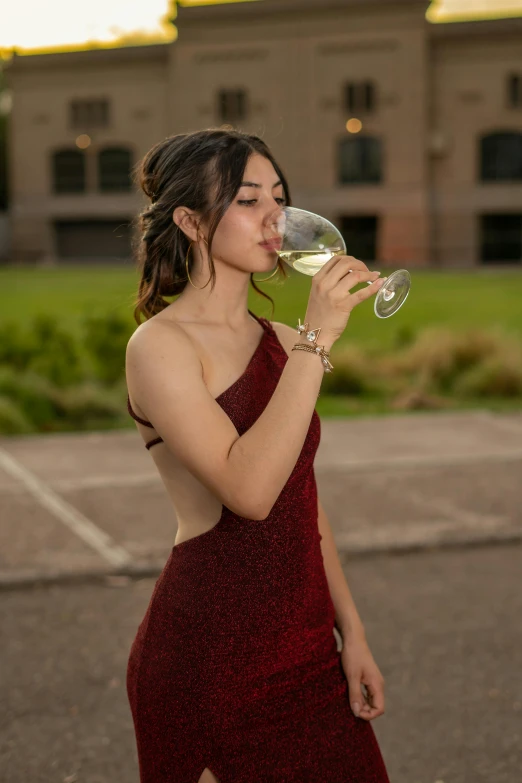 a woman in a red dress drinking from a glass